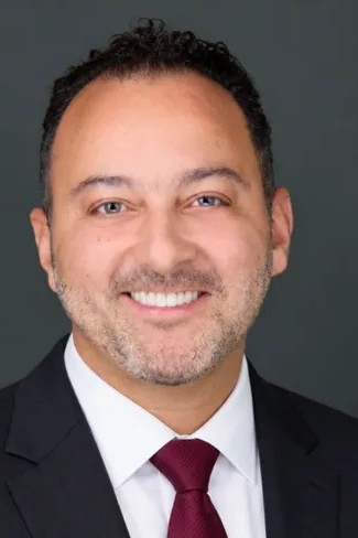 Portrait of Sherief Elsayed in a dark suit and burgundy tie